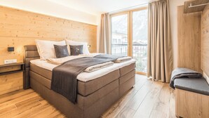 Een moderne slaapkamer met een groot bed, een houten hoofdbord en uitzicht op de omgeving.