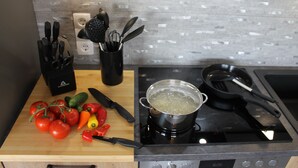 A kitchen with a stove, pots, and vegetables on the counter. - Penthouse, KingSize Bed, Queen Size SofaBed, full Kitchen, 650 MBit, Workspace (Euskirchen)