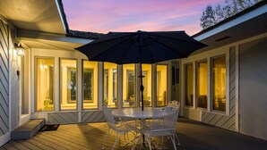 An outdoor patio with a table and chairs, an umbrella, and a view of the interior through large windows. - The Guest Wing at Kateri: Luxury Stay Waynesboro (Waynesboro)