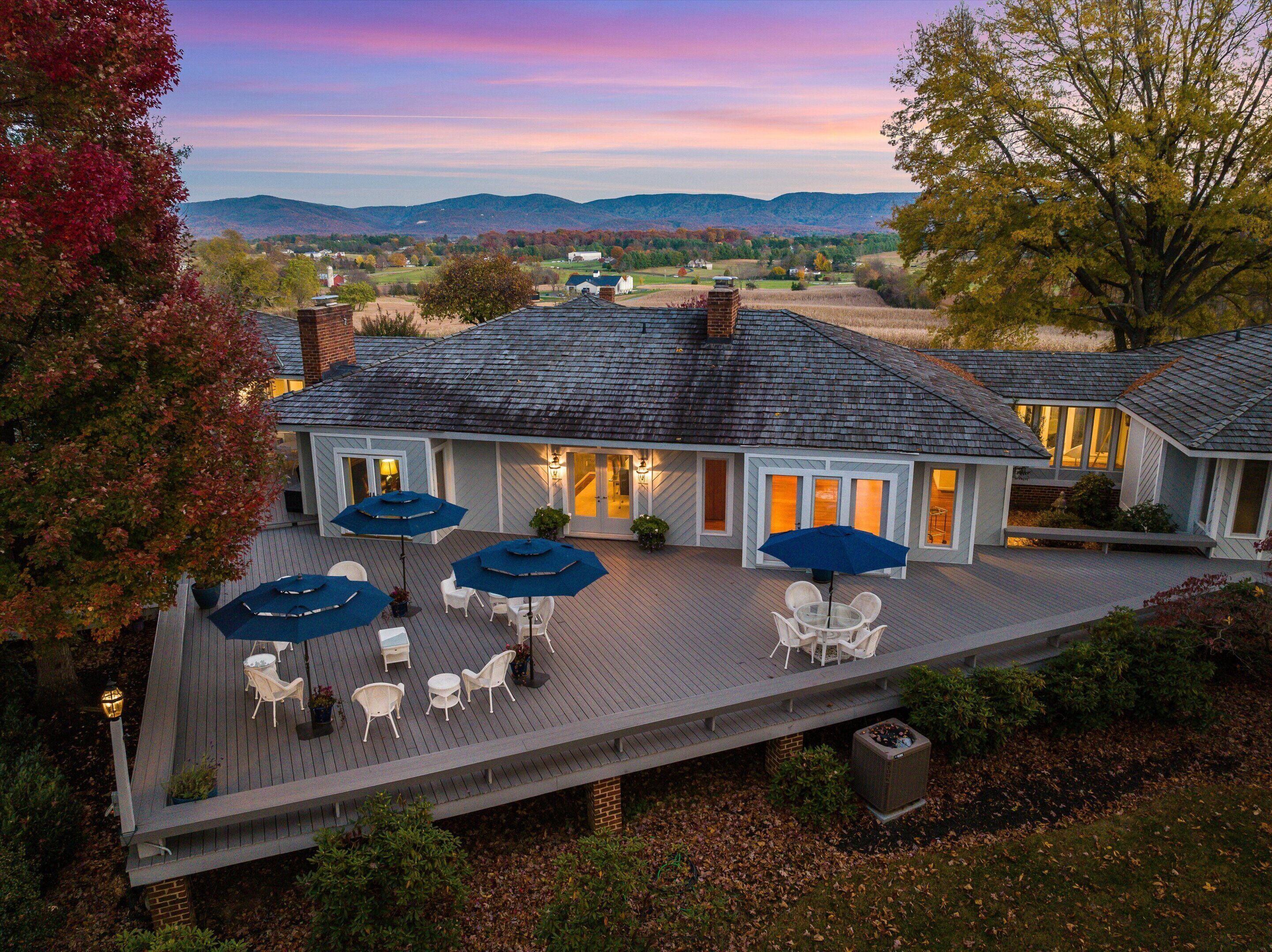 A house with a deck, outdoor furniture, and a view of the surrounding landscape.