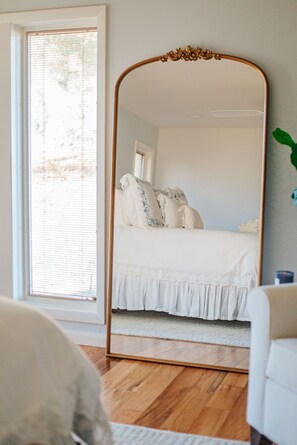 A bedroom with a large mirror, a bed with white bedding, and a window with blinds. - The Guest Wing at Kateri: Luxury Stay Waynesboro (Waynesboro)