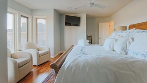 A bedroom with a bed, two armchairs, a ceiling fan, a TV mounted on the wall, and a door leading to another room. - The Guest Wing at Kateri: Luxury Stay Waynesboro (Waynesboro)