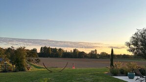 Un espacio al aire libre con césped y una vista despejada de un campo lejano y un atardecer.