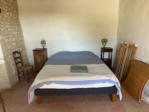 A bedroom with a bed, two bedside tables with lamps, a chair, and a wooden headboard. - Charming 300m2 house in stones, can accomodate up to 12 persons. Private pool. (Pardaillan)