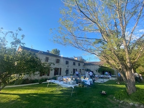 A stone building with outdoor tables set up for dining, surrounded by greenery and a clear blue sky. - Charming 300m2 house in stones, can accomodate up to 12 persons. Private pool. (Pardaillan)