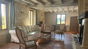 Una habitación rústica con pared de piedra, un banco de madera, un sofá y una chimenea.