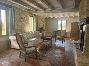 A rustic room with a stone wall, a wooden bench, a sofa, and a fireplace. - Charming 300m2 house in stones, can accomodate up to 12 persons. Private pool. (Pardaillan)