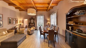 Ein gemütliches Wohnzimmer mit Holzboden, einem Esstisch für vier Personen und einer dunklen Holzkommode mit Dekorationen.