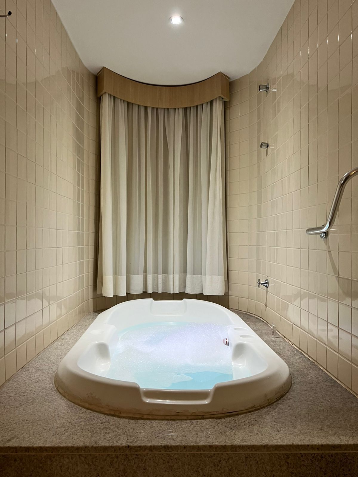 Ein modernes Badezimmer mit freistehender Badewanne, beigefarbenen Fliesenwänden und einer gebogenen Duschabteilung.