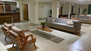 A spacious lobby with a sofa set, a coffee table, and a reception desk. - Hot Springs Flat Apart Hotel c. Banheira (Caldas Novas)