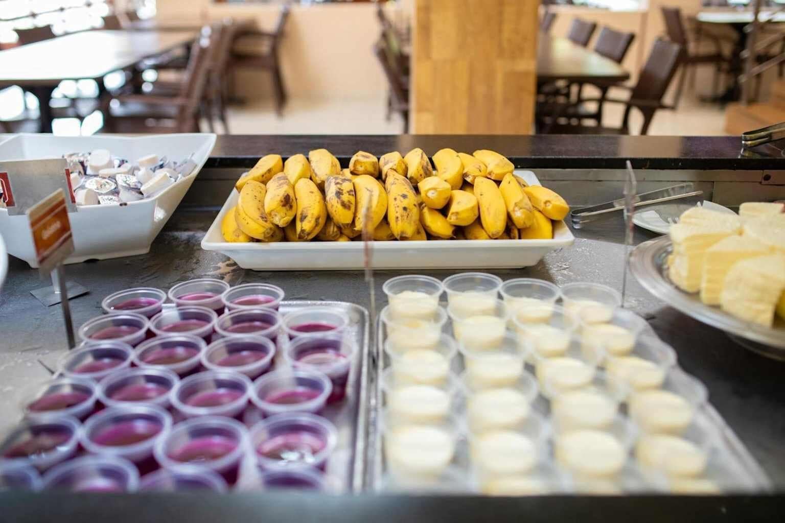 A buffet with bananas, various desserts, and beverages.