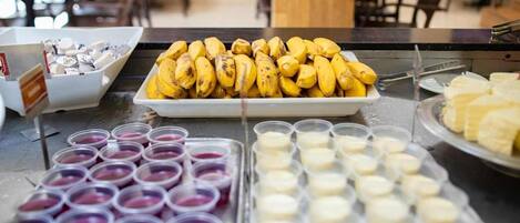 A buffet with bananas, various desserts, and beverages.