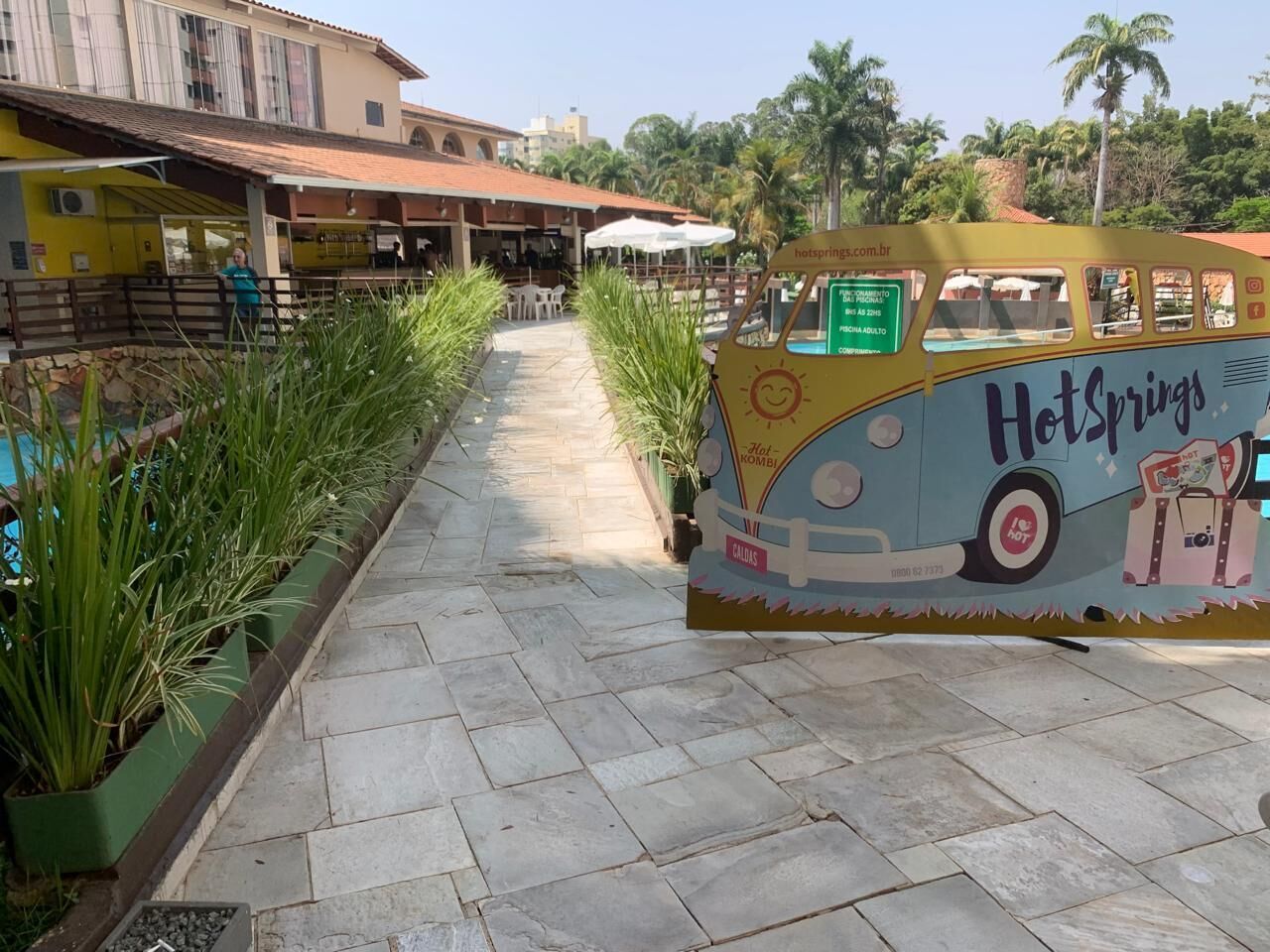 A pathway leading to a building with outdoor seating and a vintage-style food truck labeled 'HotSprings'.