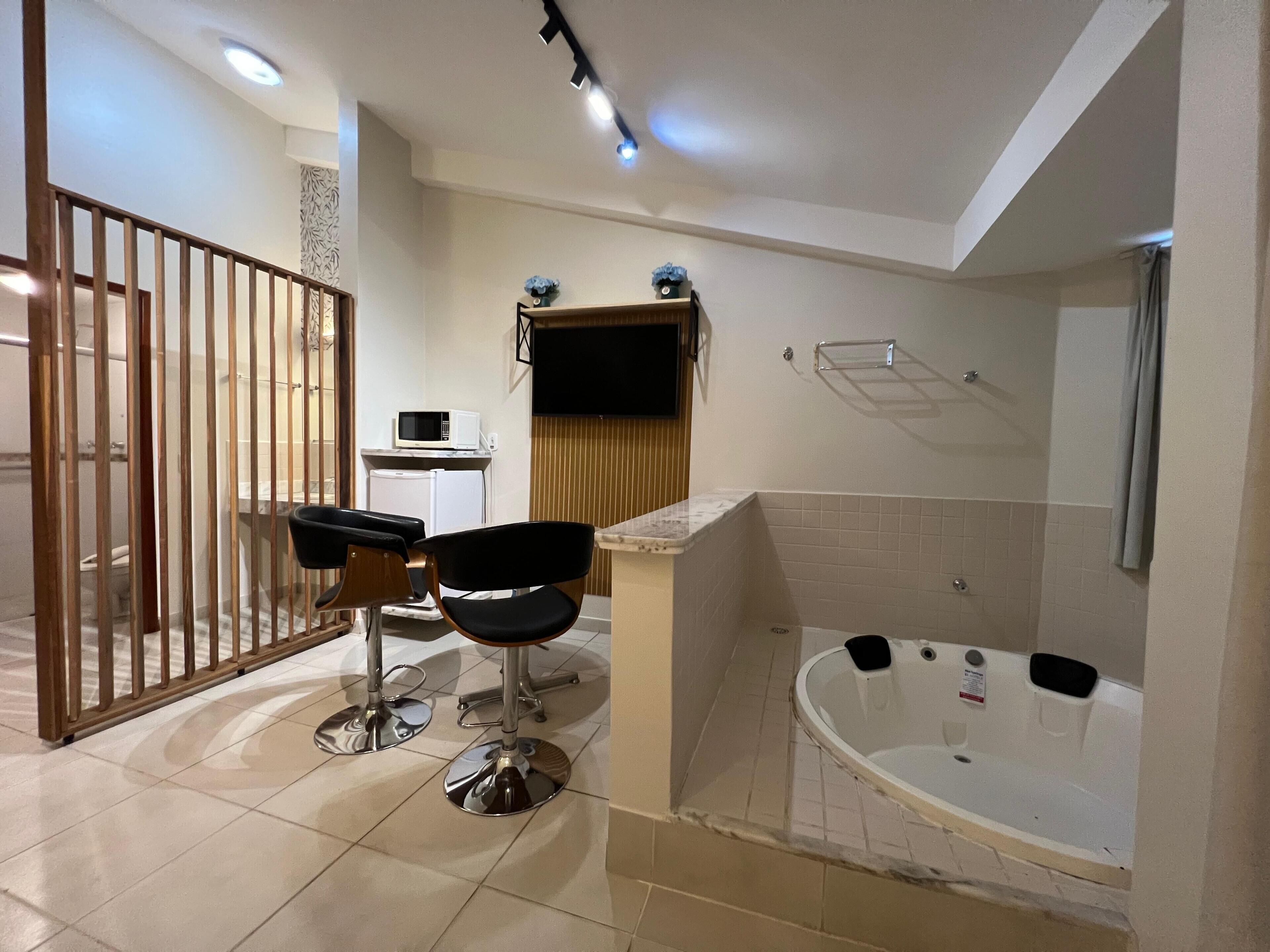 Un baño con bañera, dos sillas, un microondas y un inodoro.