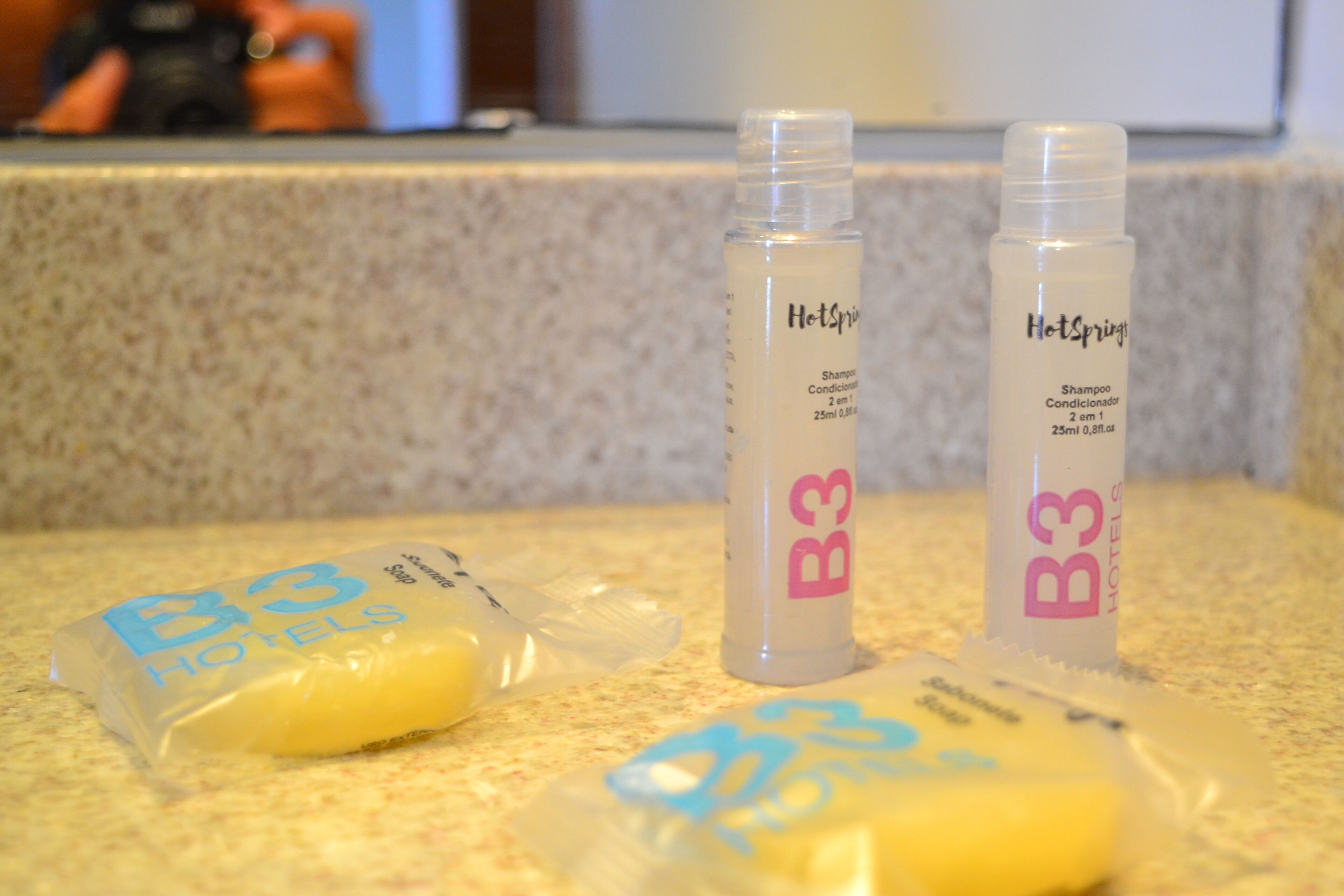 Two bottles of shampoo and two shampoo bars on a countertop.