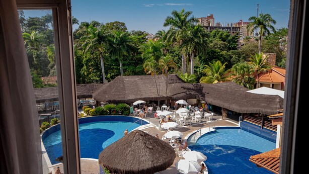 A resort pool area with multiple pools, thatched umbrellas, and lounge chairs. - Hot Springs Flat Apart Hotel c. Banheira (Caldas Novas)