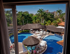 A resort pool area with multiple pools, thatched umbrellas, and lounge chairs. - Hot Springs Flat Apart Hotel c. Banheira (Caldas Novas)