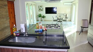 Una cucina moderna con un piano di lavoro nero, lavello in acciaio inossidabile e zona pranzo con tavolo e sedie in vetro.