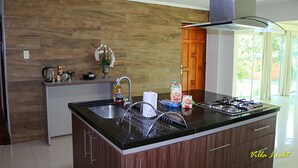 Una cucina moderna con isola centrale, elettrodomestici in acciaio inossidabile e una schiena di cotta in legno.
