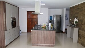 Una cucina moderna con isola centrale, elettrodomestici integrati e una parete d'accento in legno.