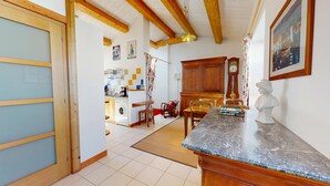 Une cuisine avec des meubles de rangement en bois, une table à manger et une horloge au mur.