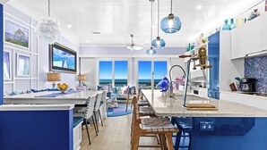 Una cocina moderna con una isla grande, taburetes de bar y vistas al océano.