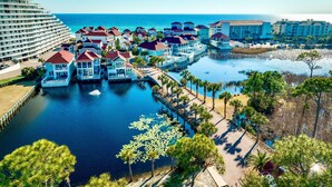 A coastal resort with overwater bungalows, a marina, and a large hotel building. - Grits-Carlton: Private beach steps away, Heated pool, Bunk rooms, Lakefront view (Miramar Beach)
