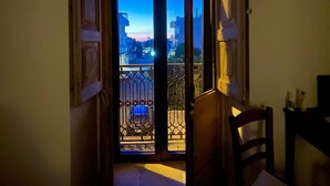 Ein schmaler Flur mit einer Tür, die auf einen Balkon führt. Der Balkon verfügt über ein Metallgeländer und einen Blick auf die Stadt.