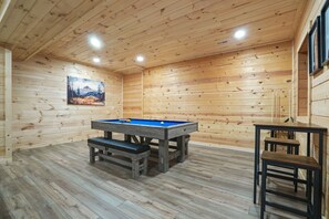Une pièce aux murs lambrés, équipée d’une table de billard et de bancs.