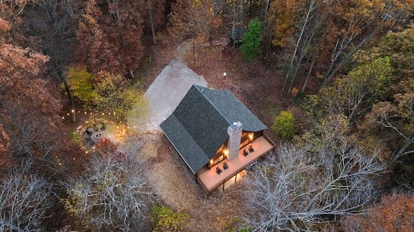 An aerial view of a cabin with a stone chimney, surrounded by a forest. - Goat Run Retreat | Hocking Hills, Hot Tub, Sauna (Logan)