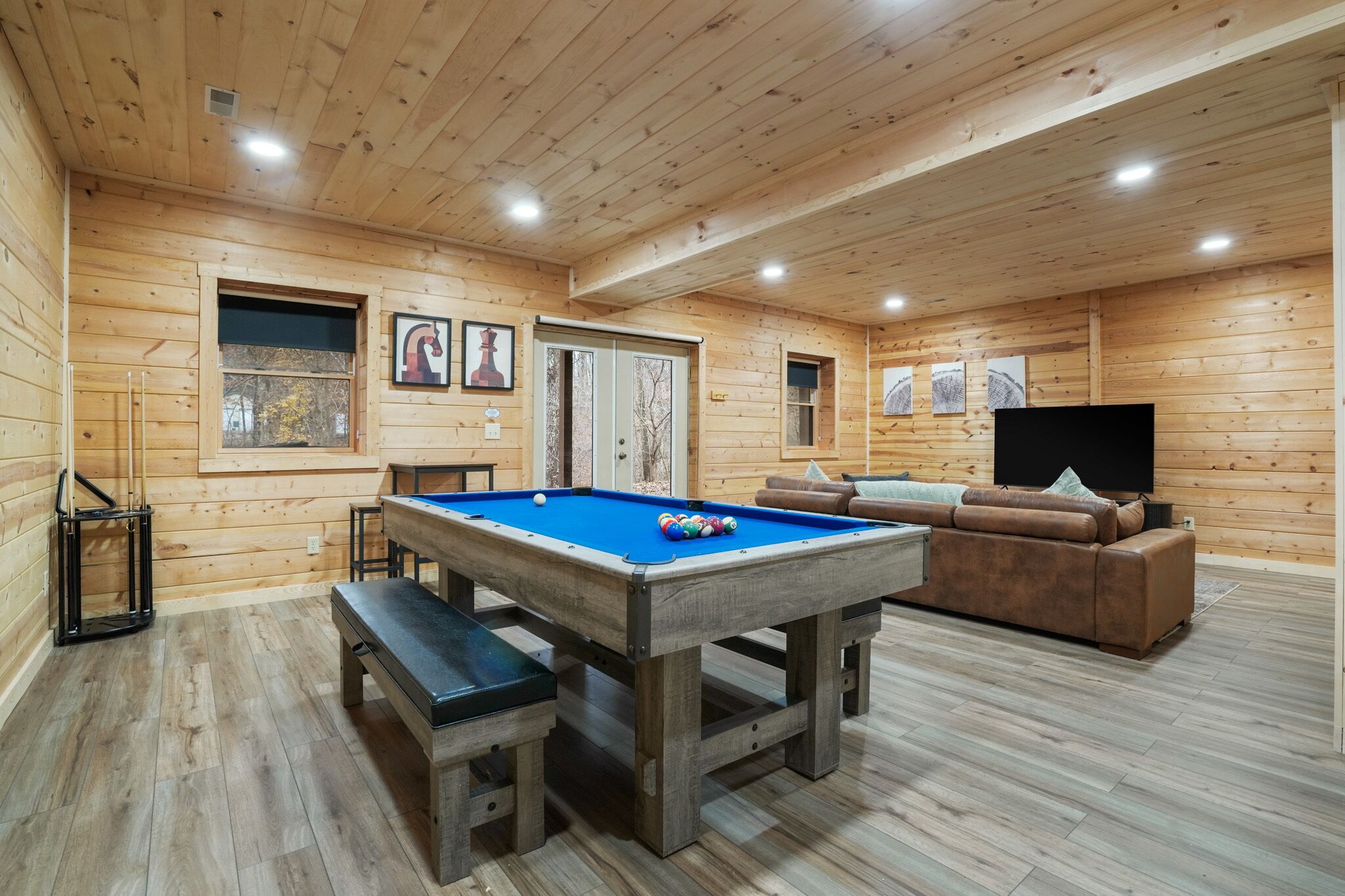 Une pièce aux murs lambrissés, équipée d’une table de billard, d’un canapé et d’un téléviseur.