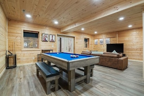 A wooden-paneled room with a pool table, a sofa, and a television. - Goat Run Retreat | Hocking Hills, Hot Tub, Sauna (Logan)