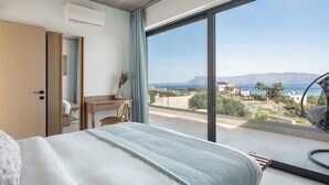 Een slaapkamer met een groot raam, een bed, een bureau en een stoel.