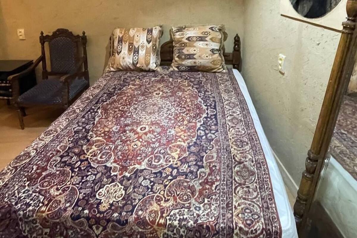 Un dormitorio con una cama grande, una silla y un espejo redondo en la pared.