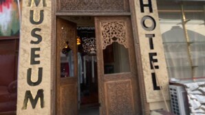 The entrance to the Old City Museum and Hotel, featuring a traditional wooden door with intricate carvings and a signboard with the museum's name. - Old City Butik Hotel (Tashkent)