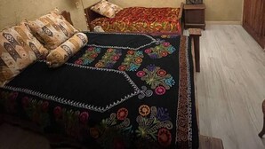 A bedroom with a bed, a nightstand, a wall-mounted lamp, a ceiling fan, a window, and a door. - Old City Butik Hotel (Tashkent)