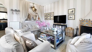 A living room with a sofa, coffee table, and television. There are striped walls and a fireplace. - Palazzo Mary in Sorrento (Sorrento)