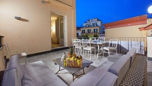 An outdoor patio with a dining table, chairs, and a fruit basket. - Palazzo Mary in Sorrento (Sorrento)