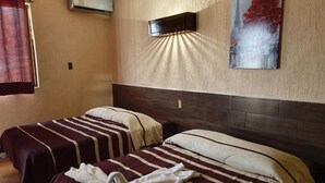 Ein Hotelzimmer mit zwei Betten, einer Wandklimaanlage und einem Stadtbild.
