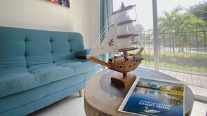 Et værelse med en blå sofa, en model af et træskib og en plakat på et rundt bord.