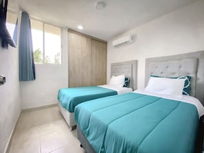 Ein Hotelzimmer mit zwei Betten, einem Fenster mit Vorhängen, einer Klimaanlage und einem gefliesten Boden.