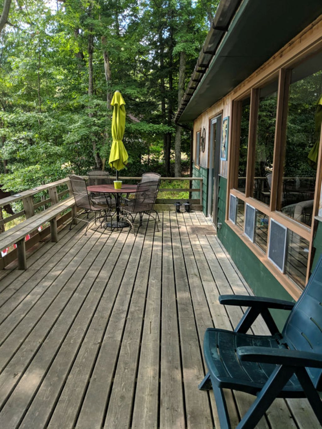 A wooden deck with a table and chairs, surrounded by trees.