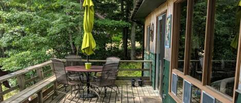 A wooden deck with a table and chairs, surrounded by trees.