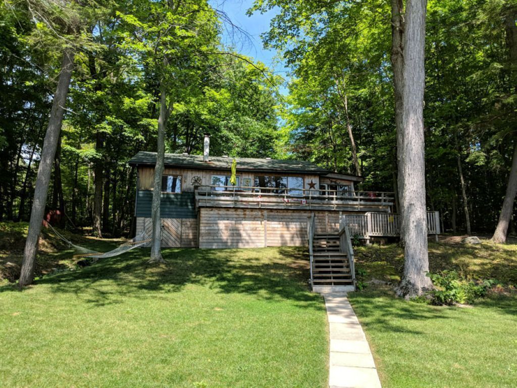 Eine Hütte mit einer Terrasse, umgeben von Bäumen.