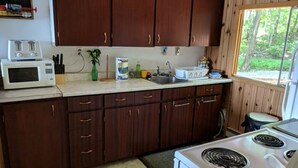 A kitchen with wooden cabinets, a microwave, a stove, and a window with a view of trees. - Oars n Smores
A place to call yours. (Georgian Bay)
