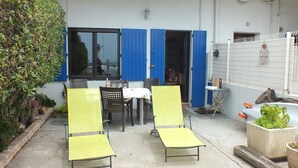 A patio with two yellow chairs, a table with a white tablecloth, and a blue door.