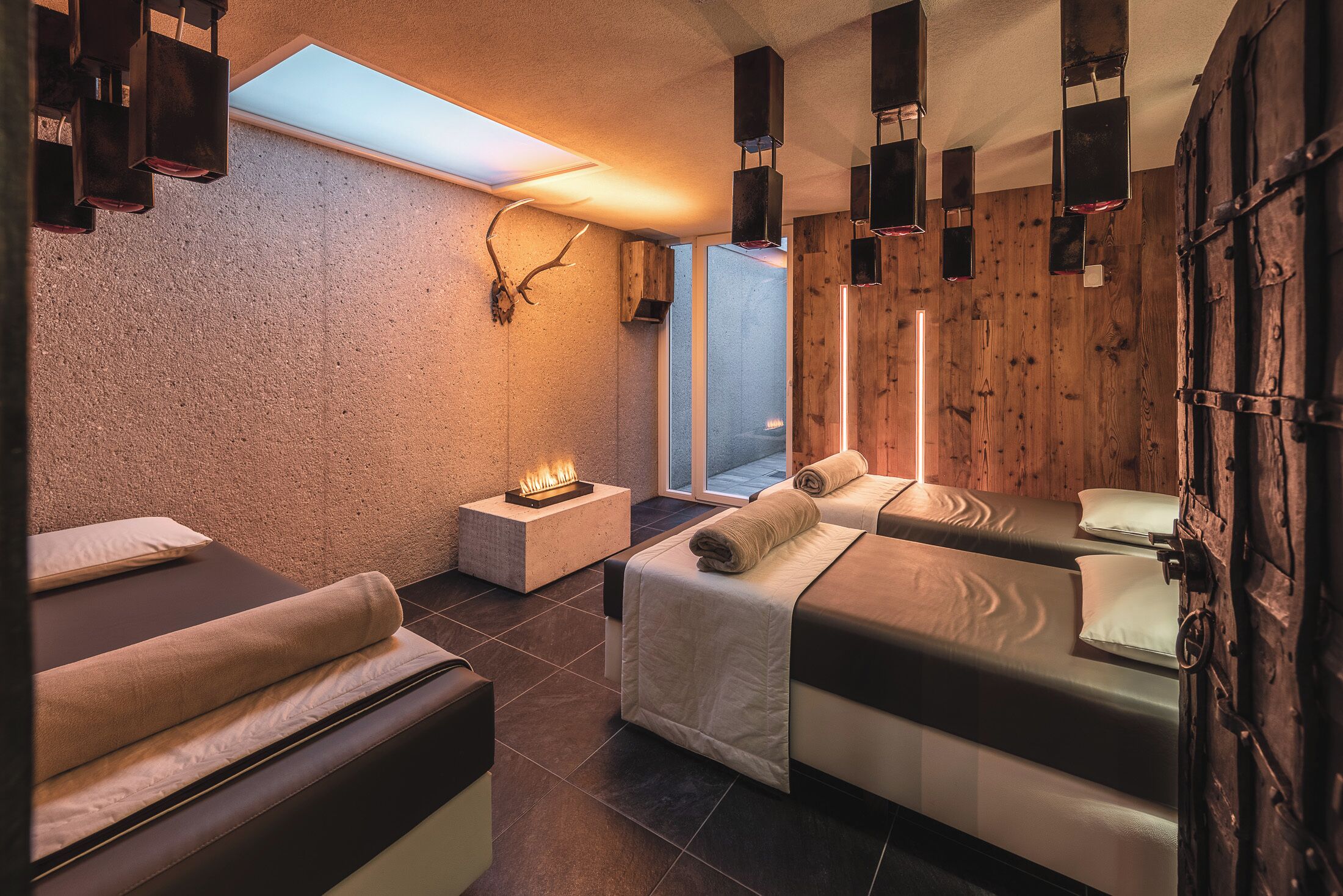 Een wellnessruimte met twee bedden, een open haard en houten wanden.