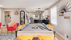 A modern living room with a pool table, yellow chairs, and a red armchair. - Private Pickleball Court+Huge Fenced Yard, Easy Access to Grand Park & Downtown (Indianapolis)