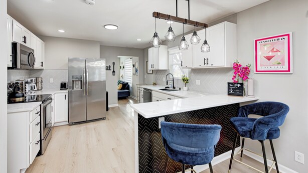 A modern kitchen with white cabinets, stainless steel appliances, and a central island with bar stools. - Private Pickleball Court+Huge Fenced Yard, Easy Access to Grand Park & Downtown (Indianapolis)
