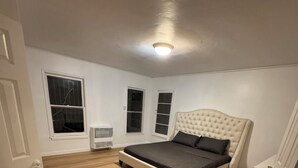 A bedroom with a large bed, white walls, and wooden flooring. - Big, Serene, Central, Perfect LA (Los Angeles)